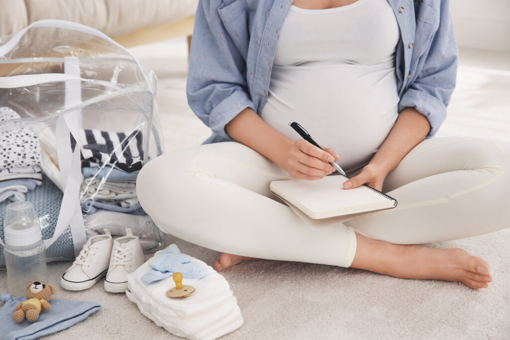 Schwangere Frau packt Tasche für Entbindungsklinik zu Hause