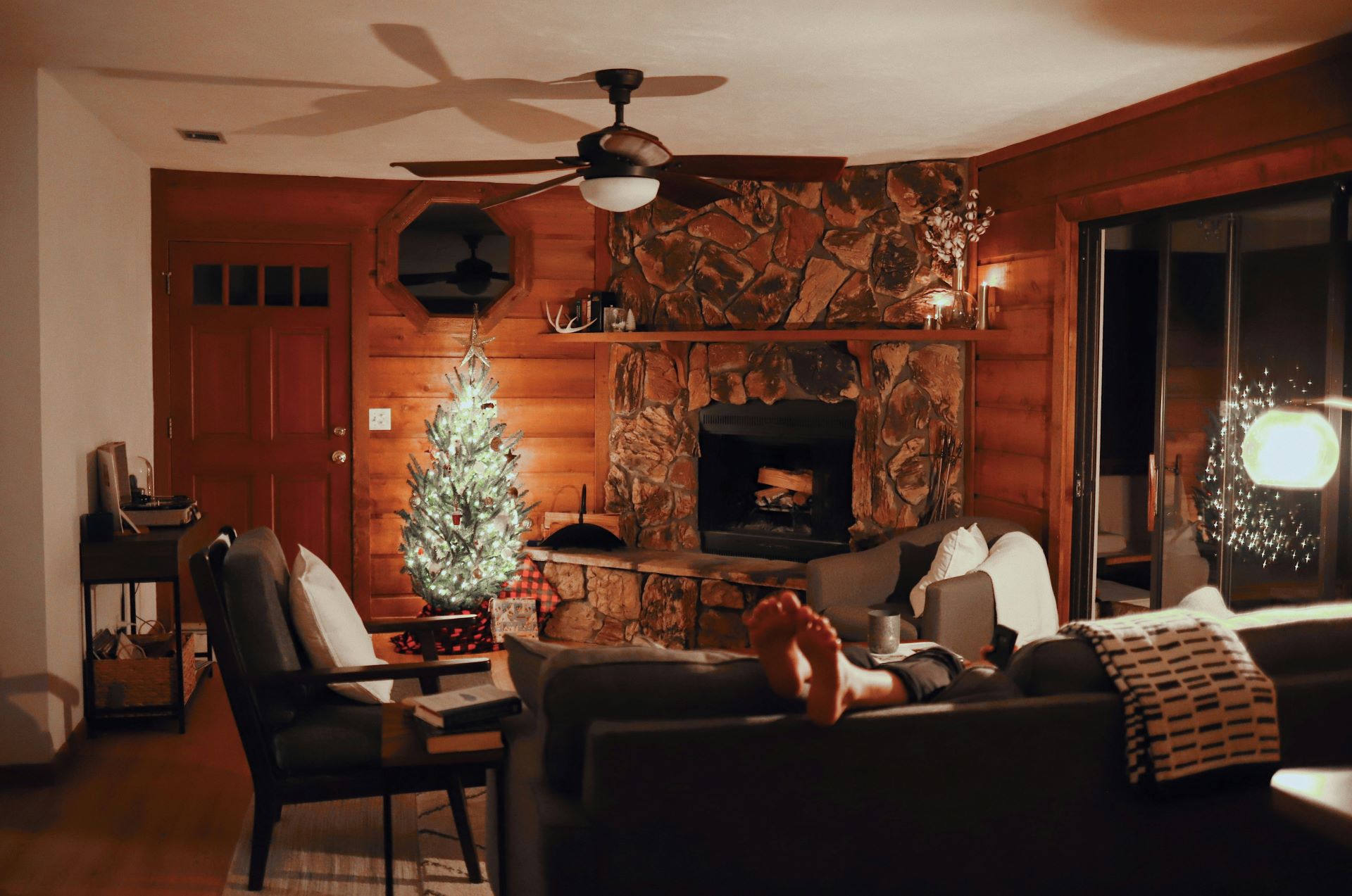 Gemütliches Wohnzimmer mit einem Kamin und weihnachtlich geschmücktem Weihnachtsbaum, warmes Licht.